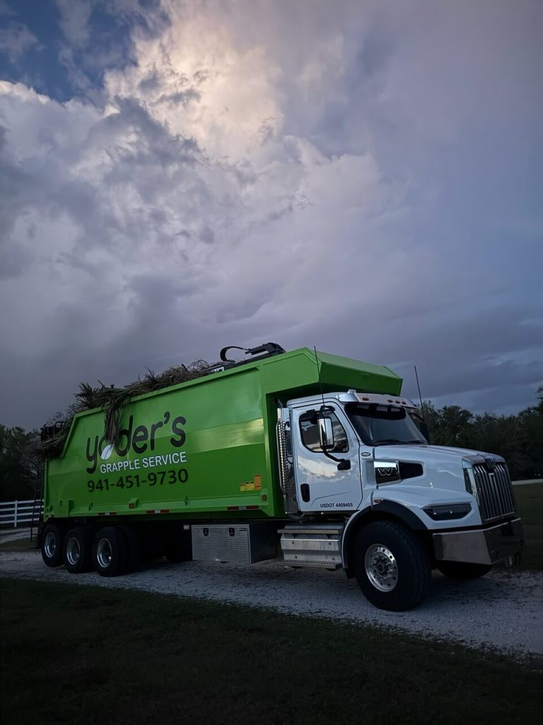 Front three-quarter view of the Yoder's Grapple Service grapple truck loaded with green waste