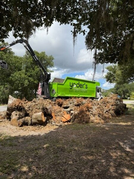 Grapple arm loading a pile of tree stumps and root balls into the truck body