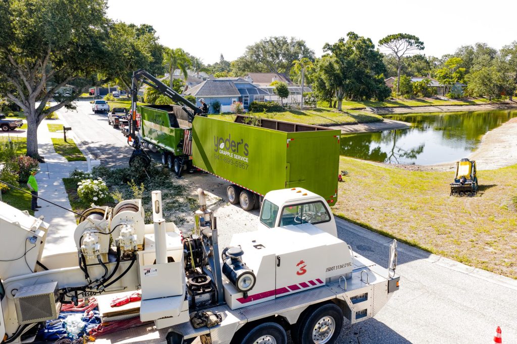 Grapple truck and trailer loading debris on a residential street in Sarasota County