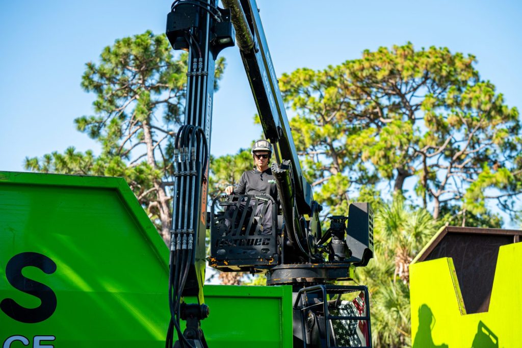 Owner-operator running the grapple arm to load green waste into the truck body