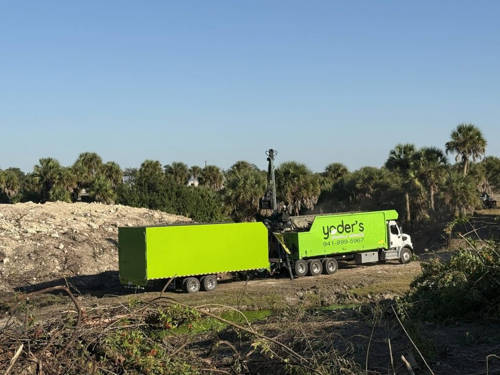 Grapple truck and dump trailer staged at a land clearing site near Sarasota, Florida
